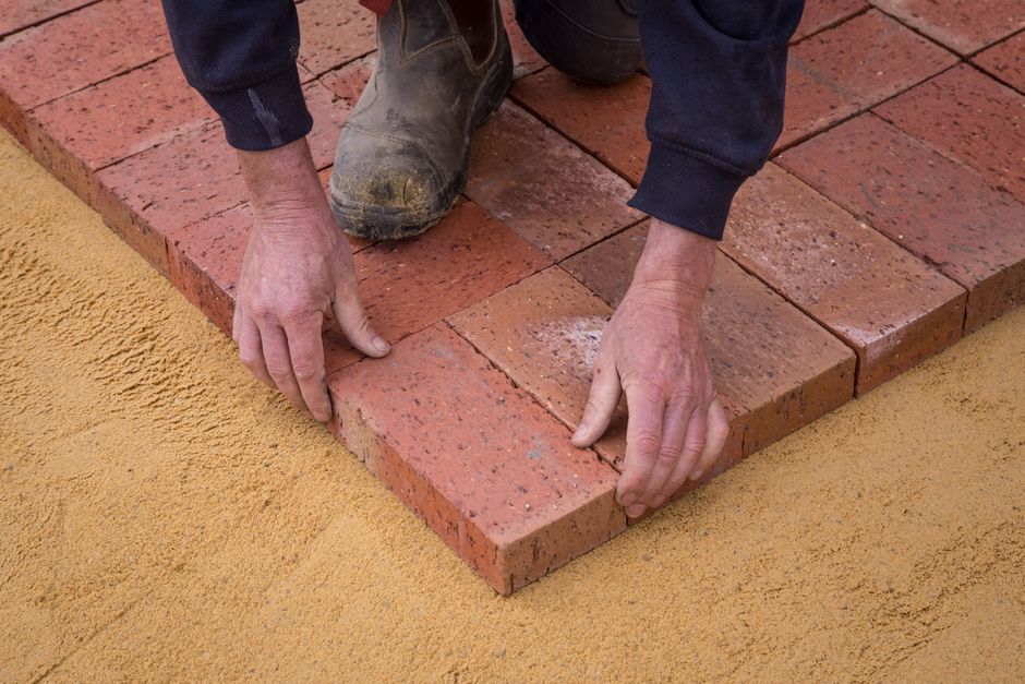 Mason laying brick pavers by hand